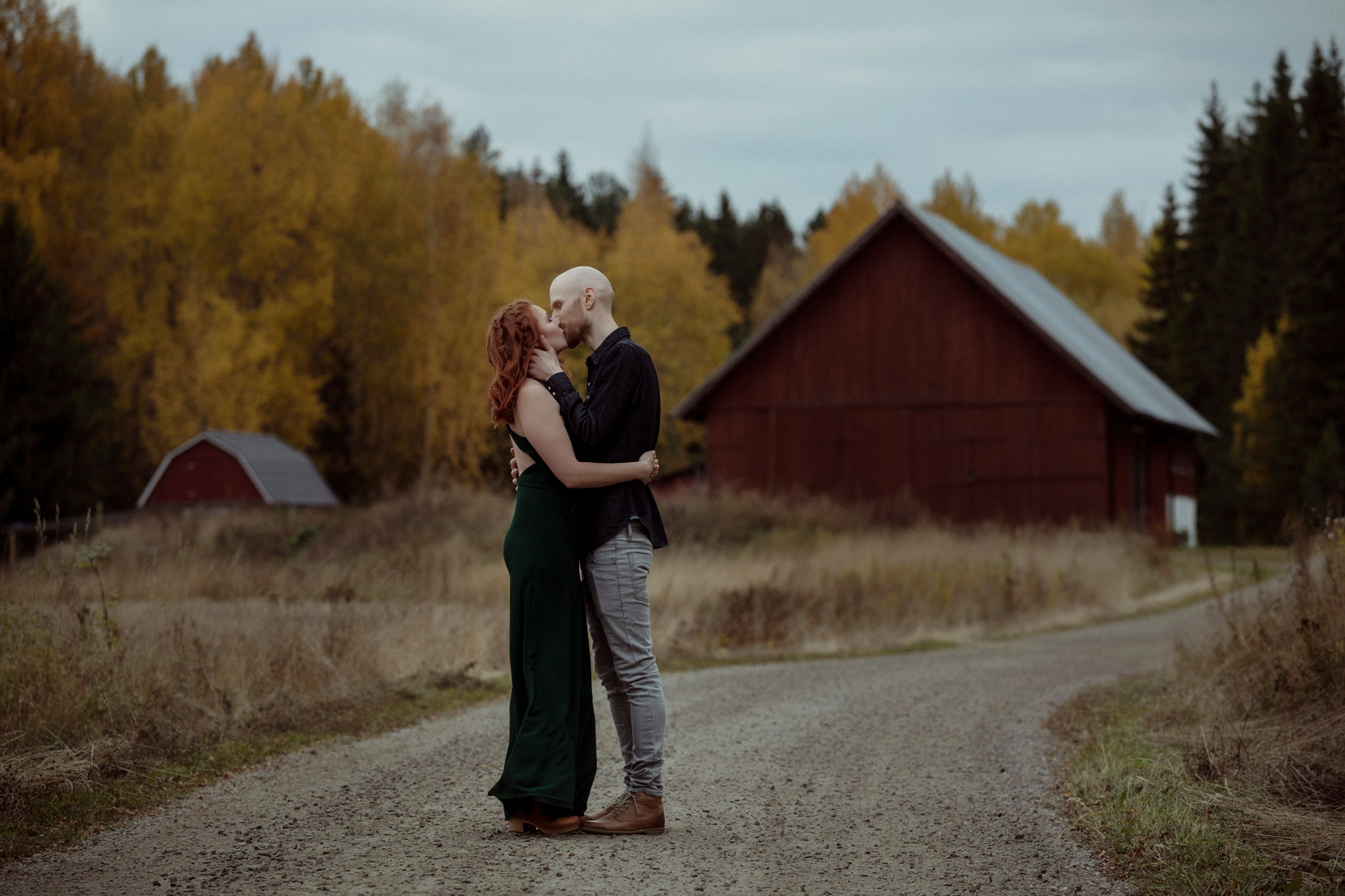 loved up beautiful ginger couple kissing in front of barn